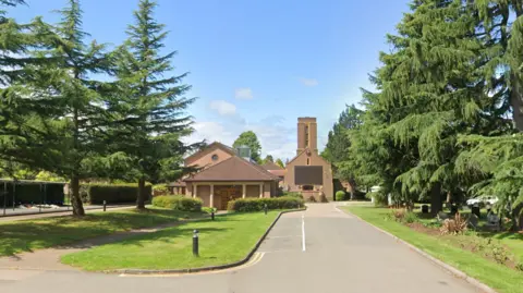 Google Canley Crematorium a large red brick building, surrounded by large trees and grass verges