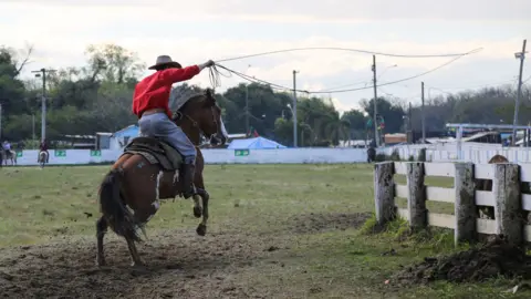 A man rides his horse, lasso in hand, during the rodeo