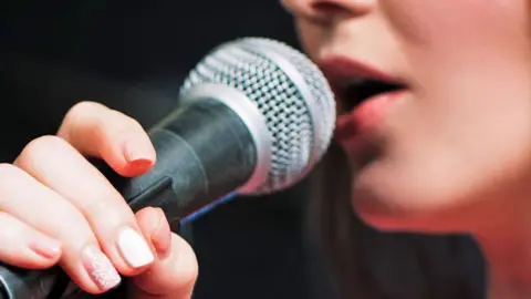 A female performer's mouth speaking into a microphone