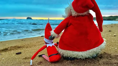 santa and elf on beach