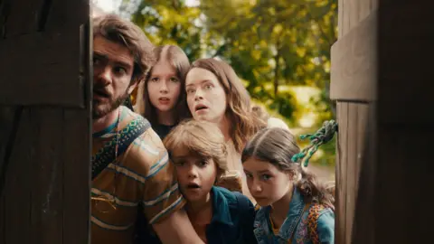 A family looks in awe through an open old door 