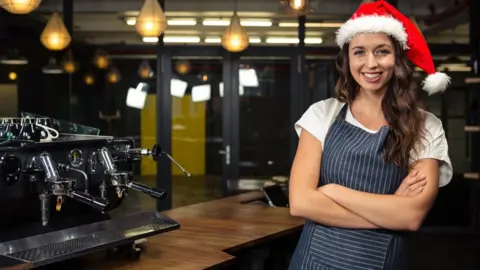 Getty Images A woman working in a coffee shop wearing a Santa hat