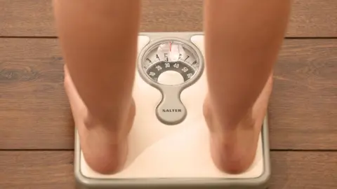 Press Association / Chris Radburn Young girl weighing herself on bathroom scales, checking her weight
