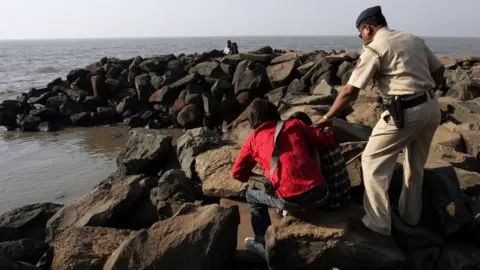 Getty Images MUMBAI, INDIA - FEBRUARY 11, 2008: Couples - A Police constable from Beat Number three of Bandra police station forces the couples cuddling on the rocks near the Searock Hotel on Bandstand on Monday evening.