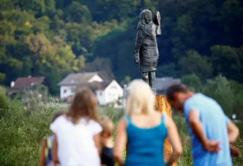 Borut Zivulovic / Reuters People look on at a bronze statue depicting US First Lady Melania Trump