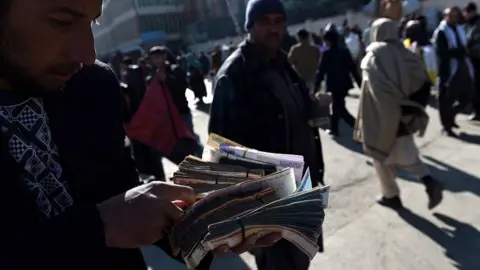 Getty Images An Afghan money changer counts Afghani currency notes at the roadside in Kabul