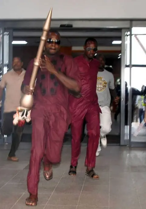 AFP A man runs holding mace, the symbol of authority of the Upper Legislative Chamber, seized at the chamber in Abuja, on April 18, 2018. The ceremonial mace of Nigeria's upper chamber of parliament was stolen Senate leaders said, condemning the theft as an 'act of treason'.