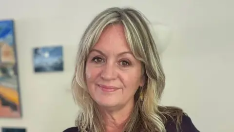 Anna Cowie A woman with long blonde hair looks at the camera