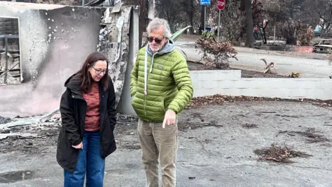 Regan Morris/BBC, Mark Worthington, and his partner Mindy Elliott, inspect their fire decoration property in Altadena