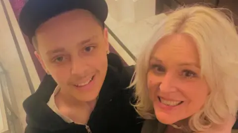 A selfie-style image of Billy and Abi Davies. They are smiling and looking into the camera. Billy is wearing a black hooded top and has his arm around Abi. 