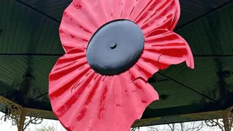 Eastleigh Borough Council A large red plastic poppy in Eastleigh bandstand, the bottom section of the poppy petal is snapped and cracked in fragments.