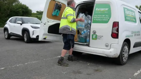 A man loads bottles of water into a van