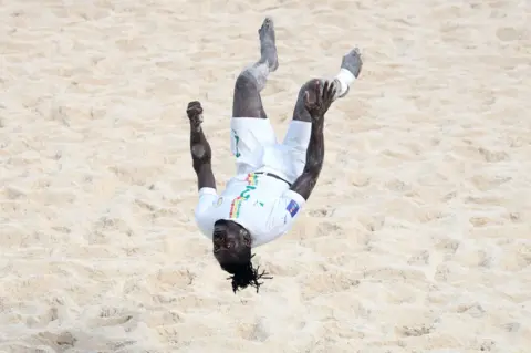 ALEX GRIMM/GETTY IMAGES Ninou Diatta doing a backflip on the sand. 