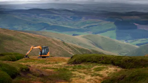 Northumberland National Park A digger at work high on a hill in Northumberland