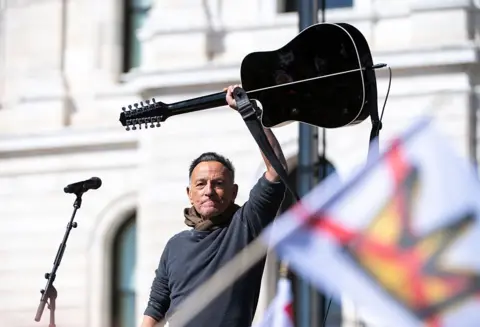 Getty Images Bruce Springsteen holds up his guitar after a performance during a rally in Minnesota. 