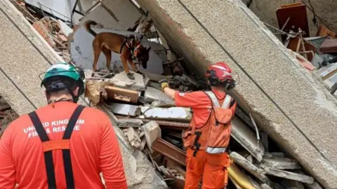 UK ISAR Two UK ISAR officers and a dog searching through rubble