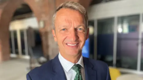 Report author Andy Haldane, looking at the camera while posing in front of a reception area