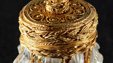 Neil Hanna A close-up of the gold embellishments on a rock crystal jar on a black background.