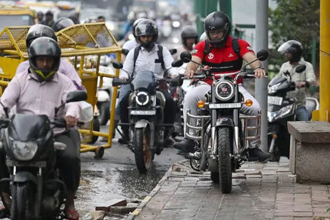 AFP via Getty Images A motorist riding on a pedestrian footpath along a bridge in New Delhi. 