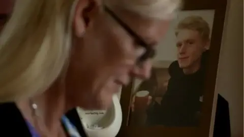 Michelle is in the foregound of this image with a photograph of her son Robert on her mantle piece in the background.