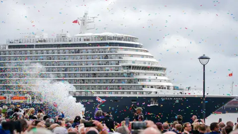 Members of the public attend the naming ceremony at Liverpool Pier Head for Cunard's Queen Anne with confetti being thrown and people flying Union Jack flags to celebrate.