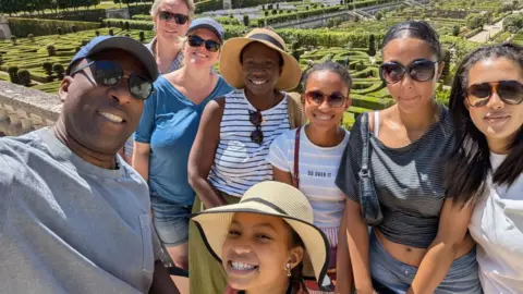 A group of eight people pose for a photo with the grounds of Chateau Villandry behind them