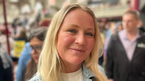 A photograph of a woman with blonde hair at the opening of the market