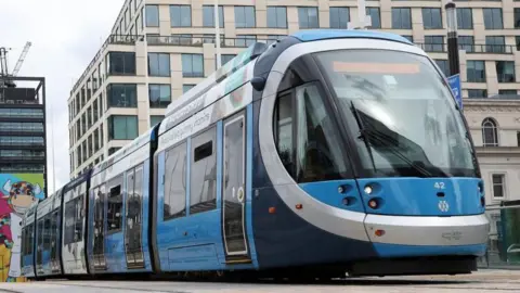 A blue and silver tram in a city centre. 