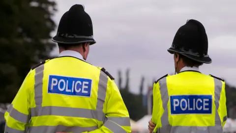 Getty Images The back of two police officers in uniform, standing outside 