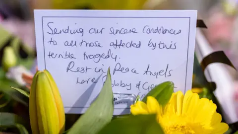 PA Media A bouquet of yellow flowers, with a message that reads: Sending our sincere condolences to all those affected by this terrible tragedy