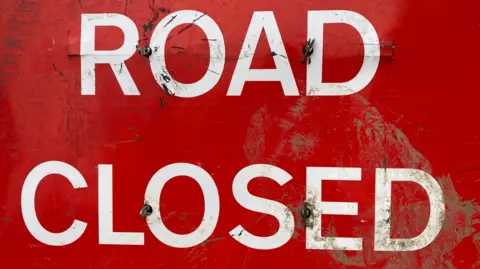 A red 'Road Closed' sign. 