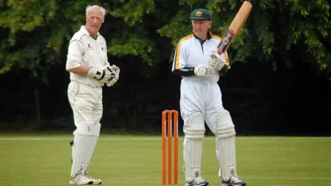 JP Photo Cooke Wicketkeeper Gerald Cooke wearing cricket whites behind the stumps, close to a batsman wearing an Australia kit.