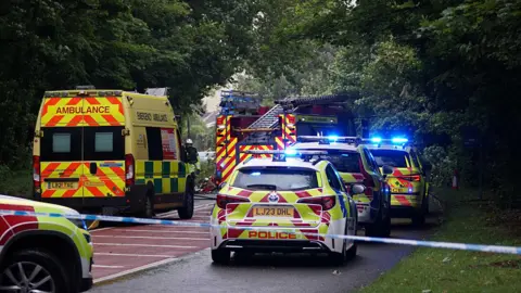 Dan Jessup Police cars and ambulance and fire engine and police tape country road in daytime