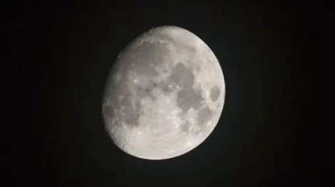 NorthEastWeatherSpotter Luna parcialmente oculta. Es blanca y se pueden ver manchas más oscuras. La foto fue tomada en Newton Aycliffe. Está rodeada de oscuridad total.