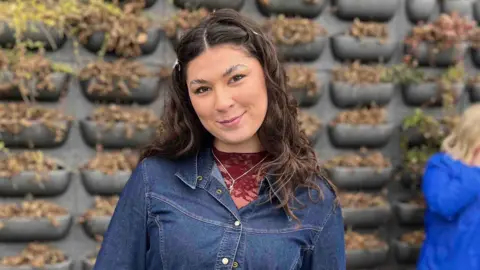 A young woman with dark hair in a full denim outfit.