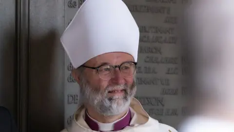 Steven Buckley The previous bishop, the Right Reverend Dr Alan Wilson, has a white beard and glasses. He is dressed in a full bishop outfit.