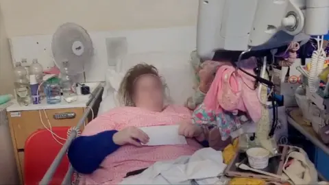 The BBC Jesse wore a pink top and a letter was surrounded by all his assets, hanging in his hospital bed, some of which are hanging from monitor. 