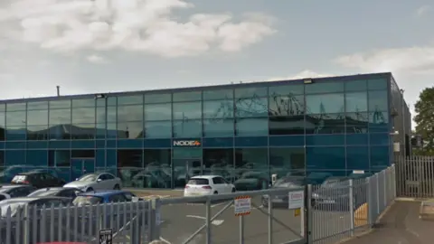 A blue glass building in an industrial park