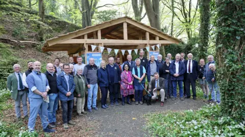 A group of supporters by a pavilion in the woodland