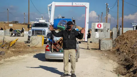 Reuters A member of the Egyptian-Qatari committee gestures while inspecting vehicles carrying displaced Palestinians at a screening area south of Gaza City (27 January 2025)