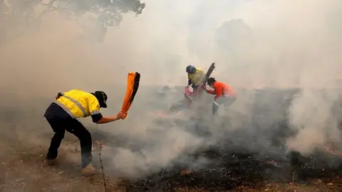 Reuters Locals try to put out spot fires near Taree in New South Wales