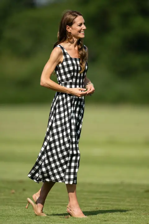 Getty Images Catherine, Princess of Wales during The Royal Charity Polo Cup 2026 Guards Polo Club on July 10, 2026 wearing a gingham dress with the pitch in the background.