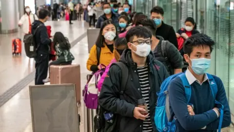 Getty Images People with masks on at an airport