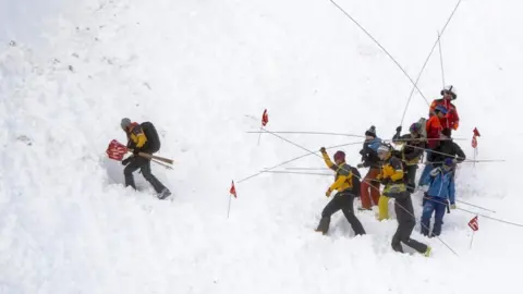 EPA Rescue forces and helicopters search for missing persons after an avalanche swept down a ski piste in the central town of Andermatt in canton Uri, Switzerland