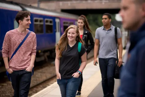 Getty Images A group of young people walking along a train platform