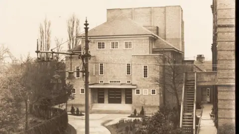 Joseph Rowntree Theatre A black and white image showing a theatre on the left with a link to the adjacent factory building