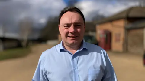 Alex Dunlop/BBC Drew Mullin wearing a blue shirt standing in the courtyard of Woburn Safari Park  