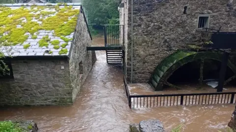 Farm house with mill in country park surrounded by flood waters