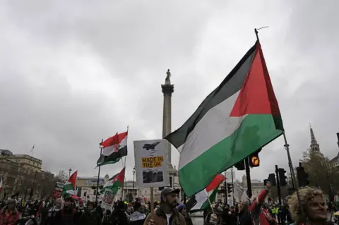 PA Media Palestinian flags being carried through Trafalgar Square in central London