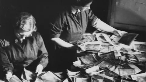 Historic England Archive Two Women's Auxiliary Air Force (WAAF) trainees sorting through piles of aerial photographic prints during training at the No.2 School of Photography in Blackpool